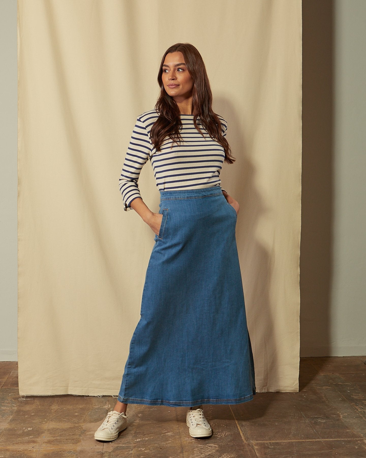 Full-length front view of model with hands in pockets of Lottie palewash denim maxi-skirt.