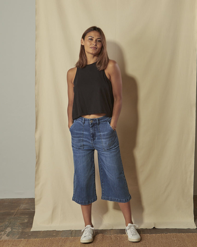 Full length front view of model with hands in front pockets of Lucia women's denim culottes.