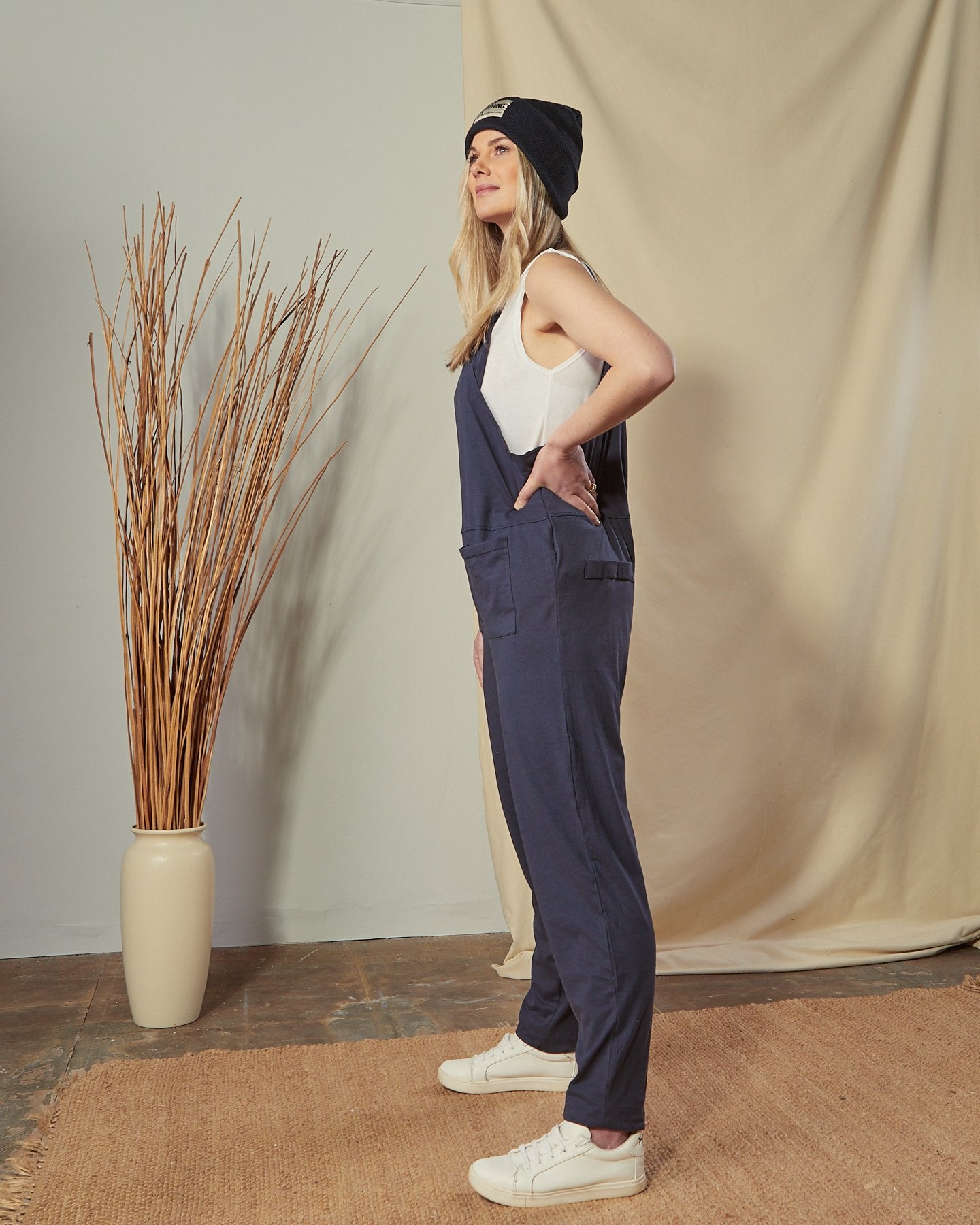 Full-length side shot of model with  hand on hip wearing cotton jersey navy Jumpsuit.