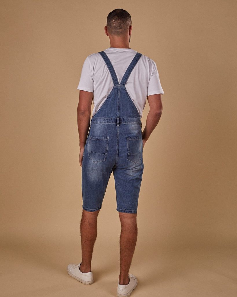 Full-length back view of model wearing Oliver denim dungaree shorts with view of belt loops, back pockets and back straps.