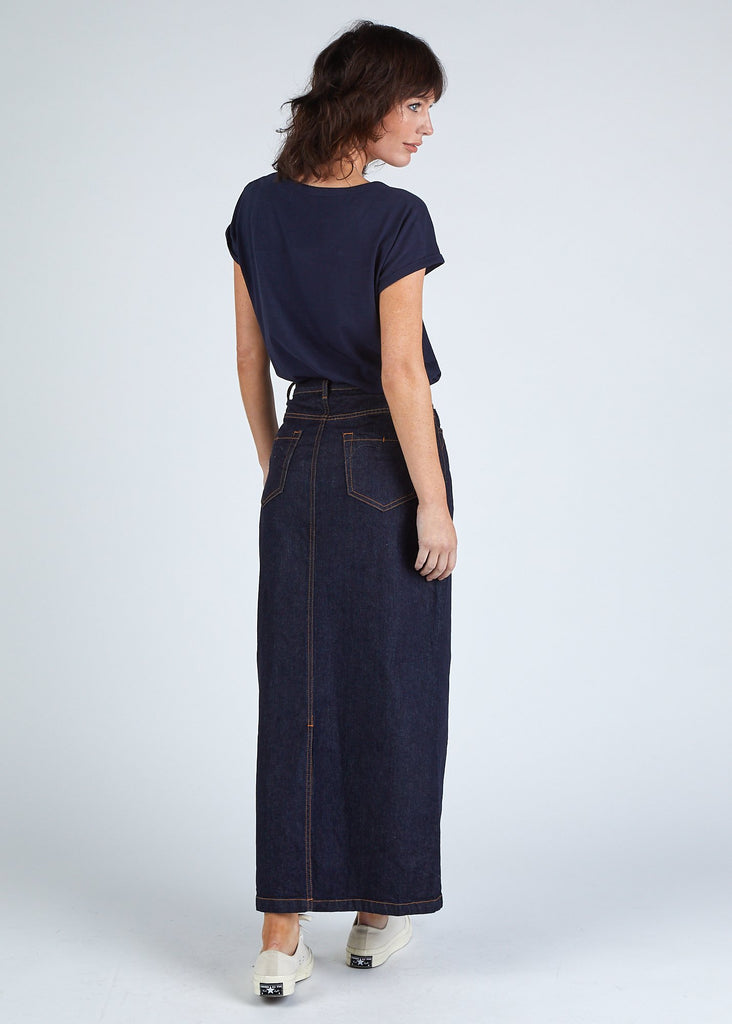 Full length, angled rear view of dark, ankle length denim skirt with view of back pockets.