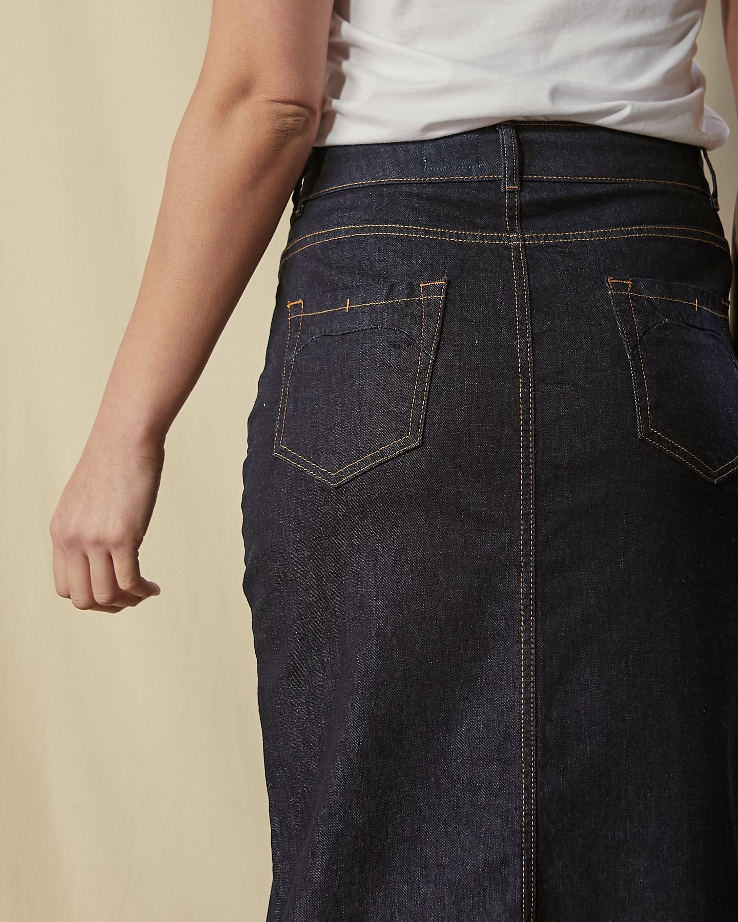 Close back view of stretchy, organic cotton, long denim skirt showing back pockets and belt loops.