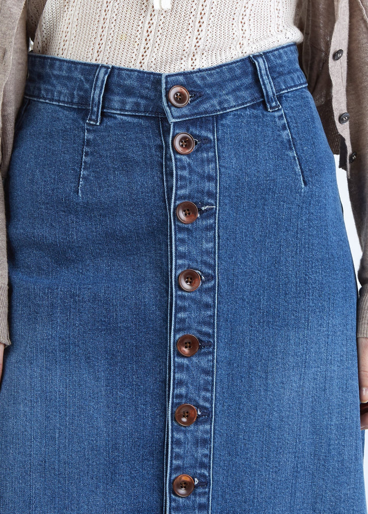 Close-up, midriff view of ‘Peggy’ blue denim skirt with focus on belt loops, button front and organic blue cotton denim.