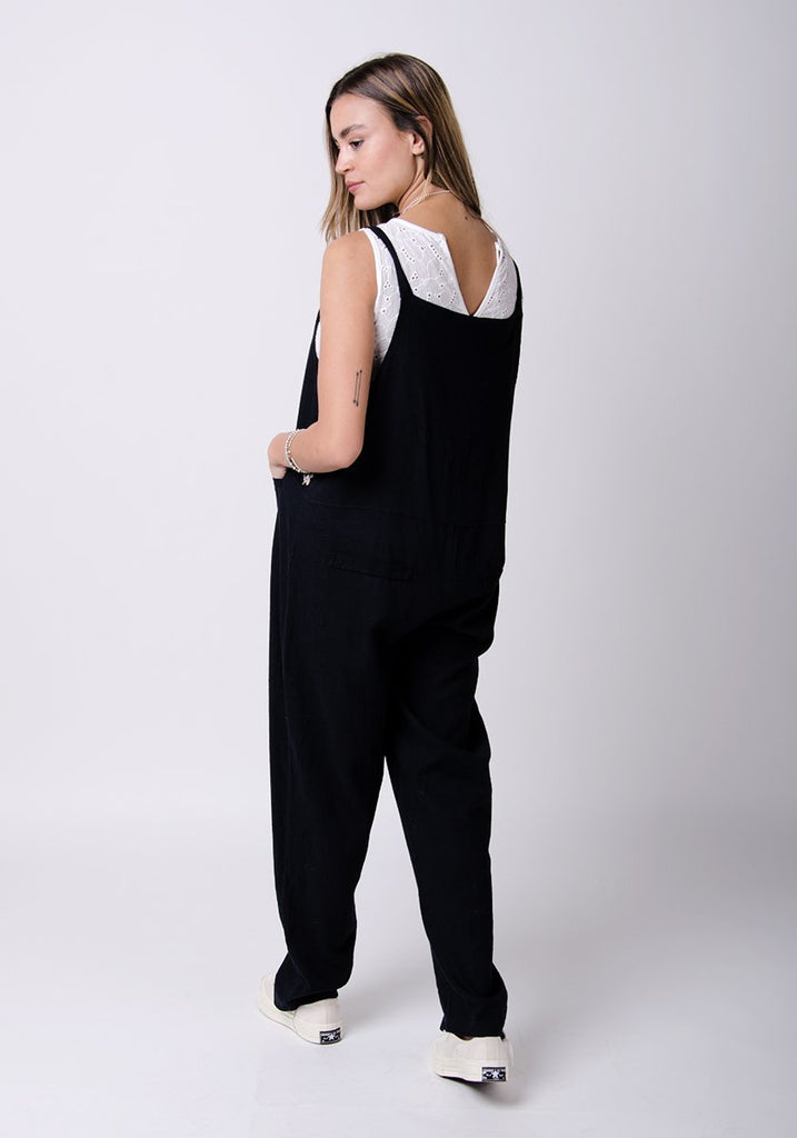 Full-rear pose looking to her left, showing adjustable straps and back pockets.