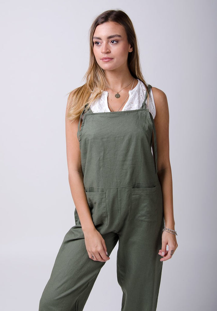 Two-thirds pose wearing basic linen, dungaree style jumpsuit.