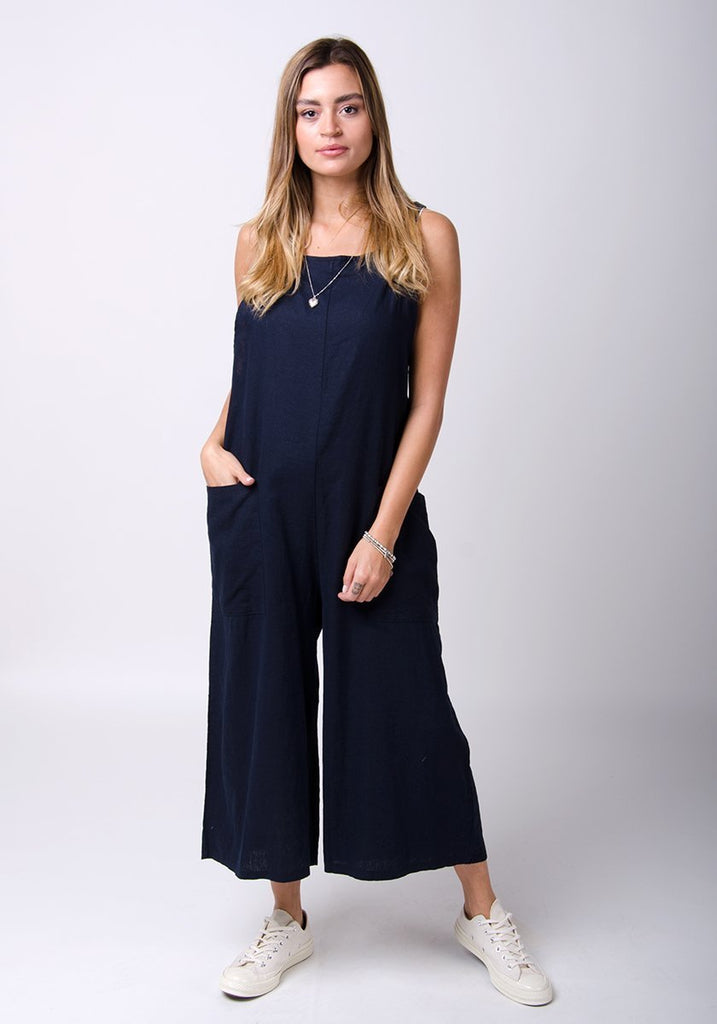 Full-length front pose with hands in right pocket wearing Saffy-style, loose fit dungarees.