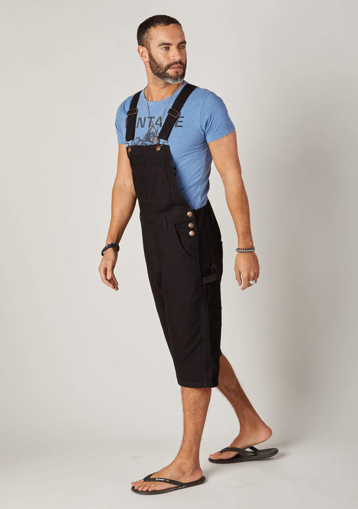Full side pose facing to left, wearing black cotton dungarees.