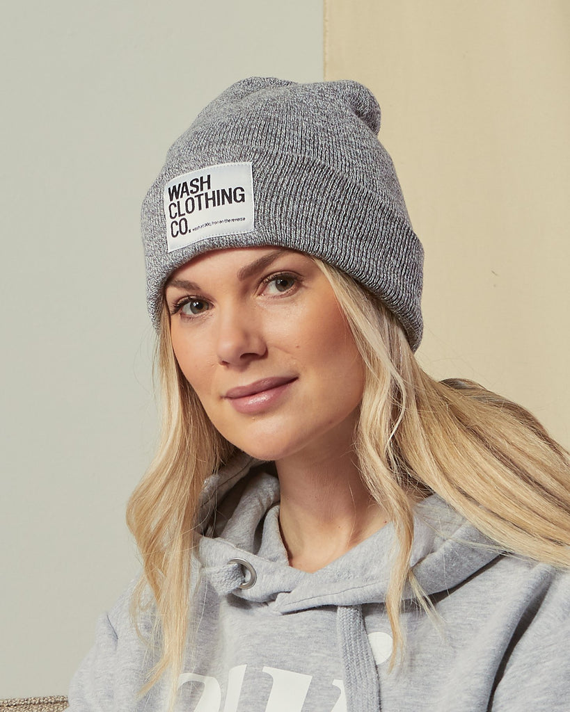 Close-up of model wearing Sinead acrylic grey cuffed beanie with view of WASH label.