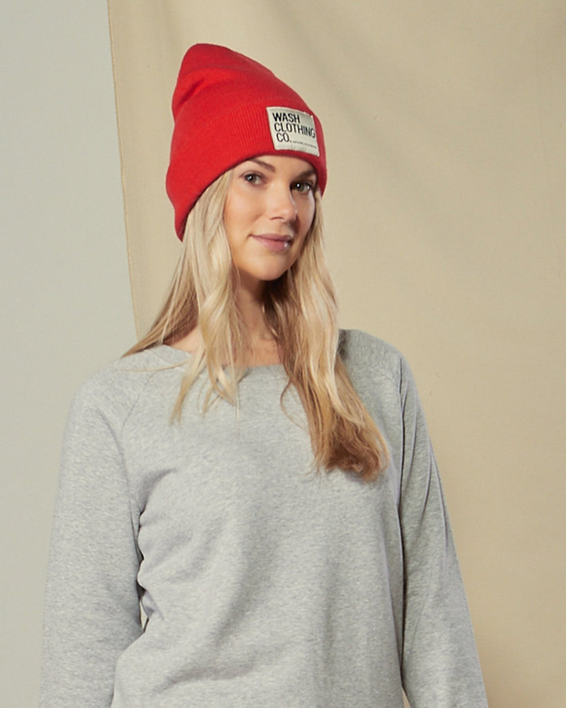 Top-half front view of model wearing Sinead red cuffed beanie paired with grey marl sweater.