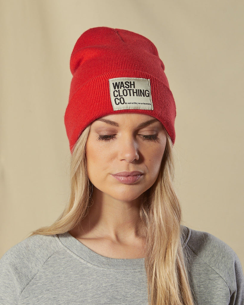 Model looking down wearing Sinead red cuffed beanie with view of WASH CLOTHING CO. label.