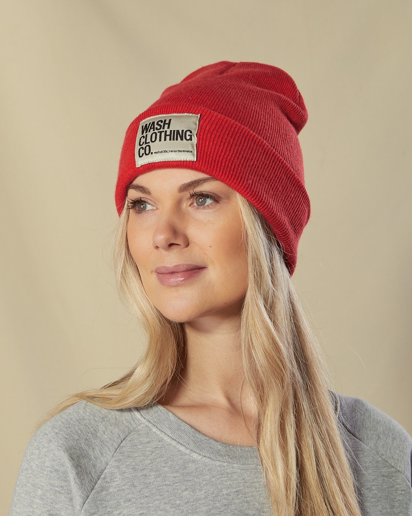 Model looking to her right wearing Sinead acrylic red cuffed beanie with view of WASH label.