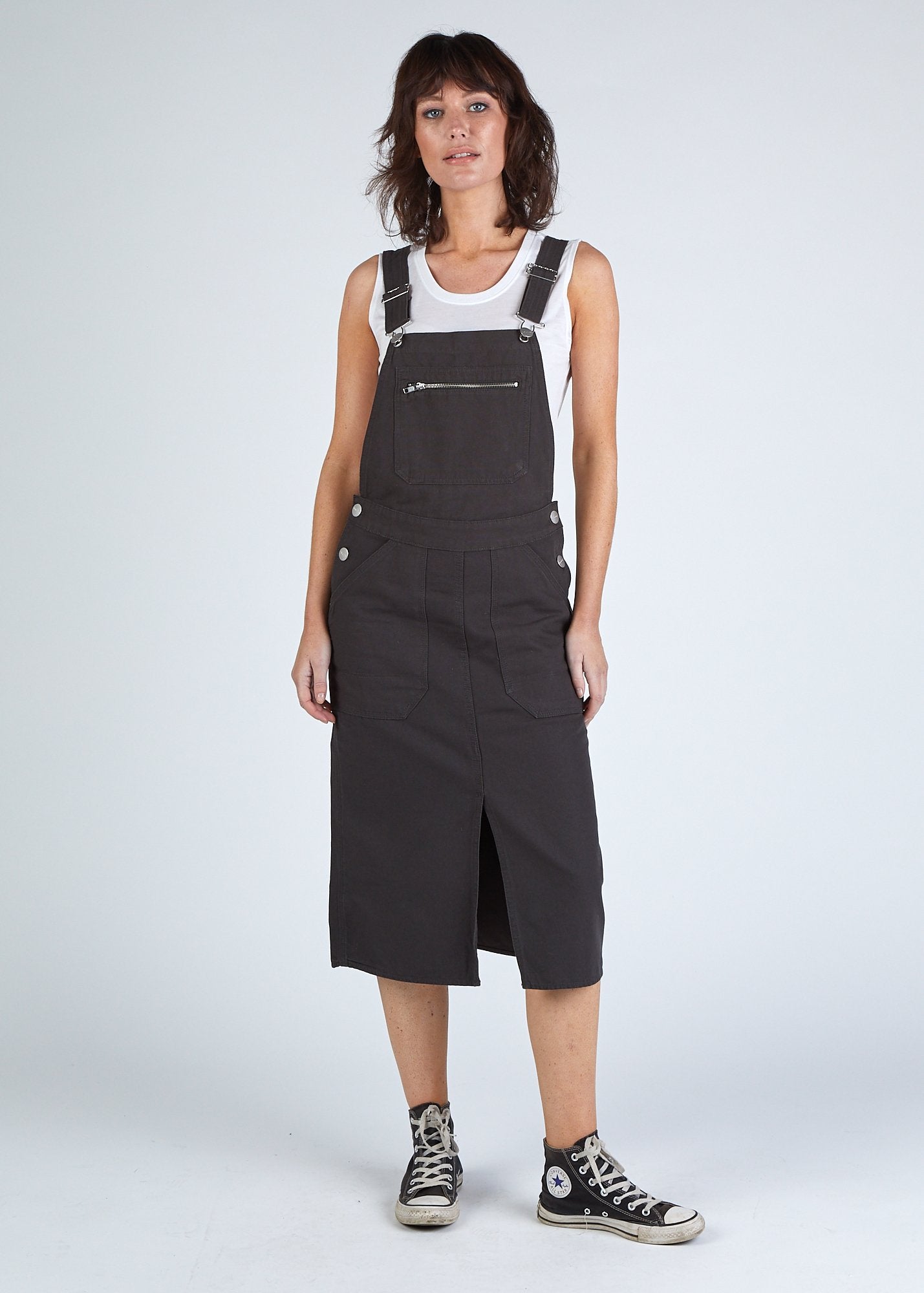 Front shot faded black Uskees organic cotton bib-overall midi dress with view of front split and deep front pockets.