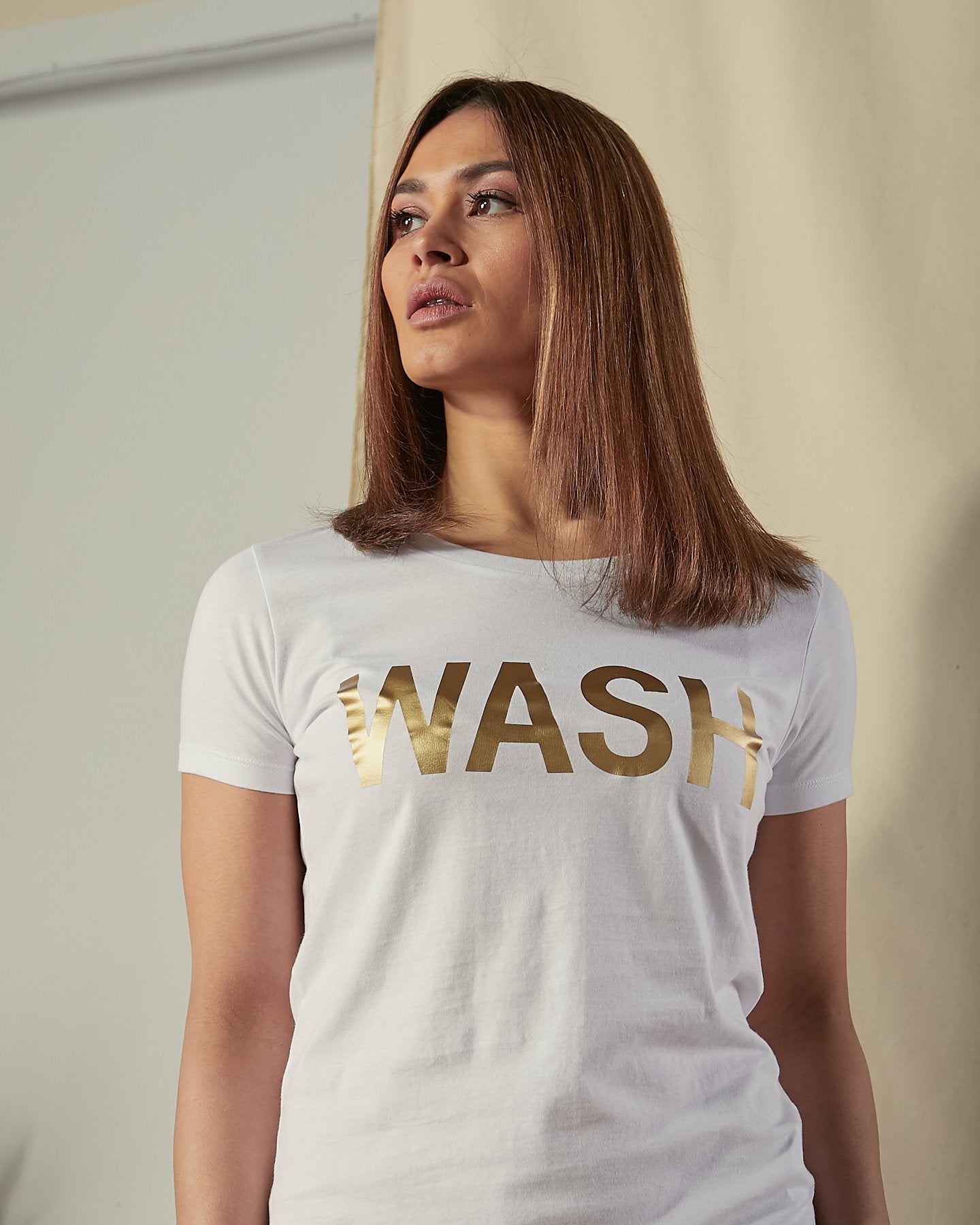 Close view of gold 'Wash' motif on white background of organic cotton crew neck t-shirt.