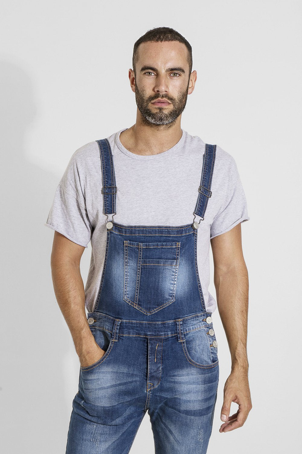 Top two-thirds view of narrow cut distressed denim dungarees with clear view of bib pockets, front pockets, fly zip and 3-button closure.