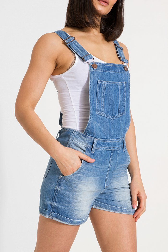Angled close-up of mid area of Xenya lightwash denim dungaree shorts with view of bib pocket, adjustable straps, belt loops and front pockets